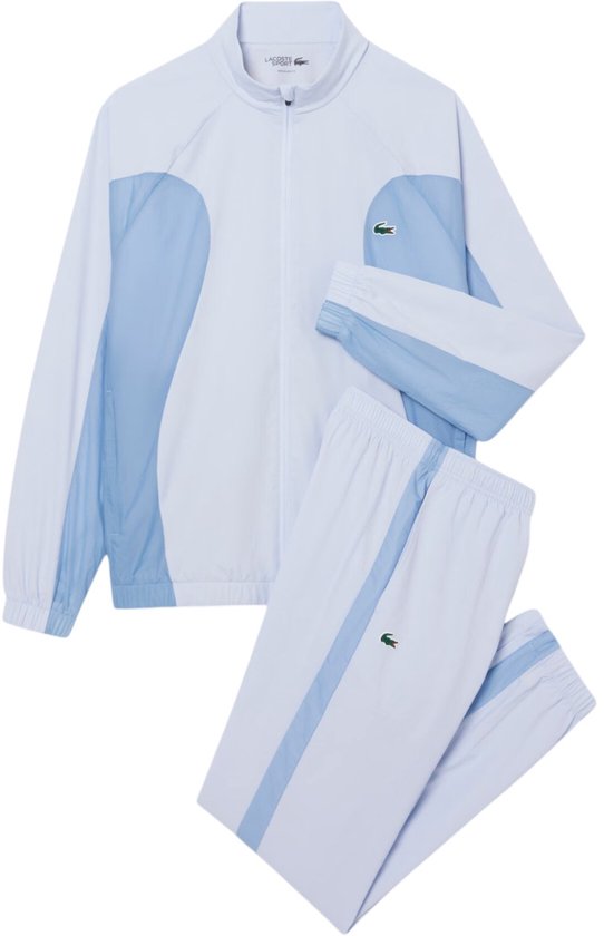 Blauw trainingspak bestaande uit een lichtblauwe jas en broek. Jas en broek hebben babyblauwe accenten en een groen Lacoste krokodillenlogo.