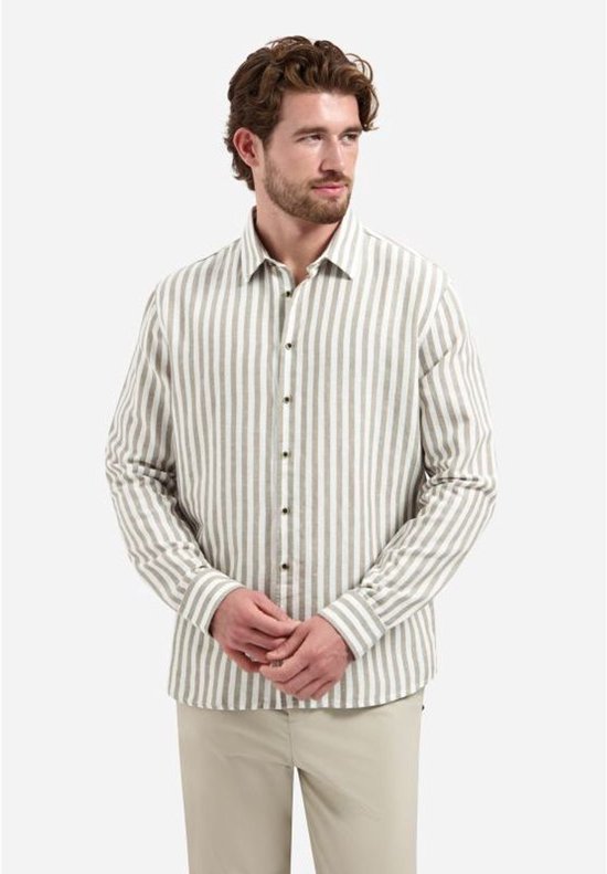 Model draagt een beige overhemd met verticale, brede witte en taupe strepen. Hij draagt er een beige pantalon bij.