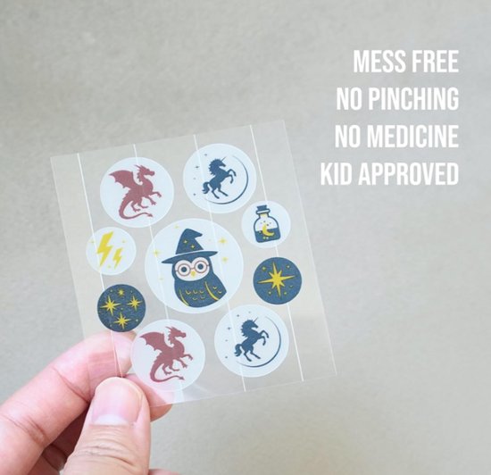 Een hand houdt een vel met 9 ronde stickers vast met magische thema's: draken, eenhoorns, uilen, sterren, een toverdrankflesje.