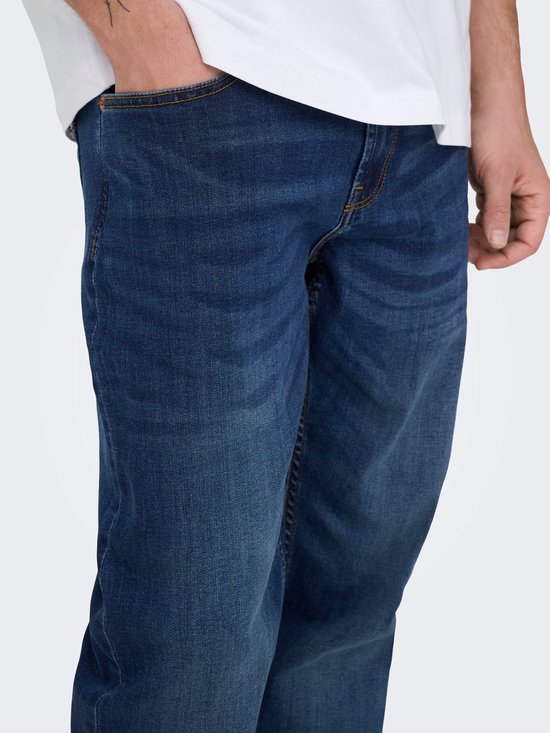 Detail van de zijkant van een man in een donkerblauwe spijkerbroek.