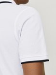 Close-up van de rechtermouw van een witte poloshirt met zwarte biesjes.