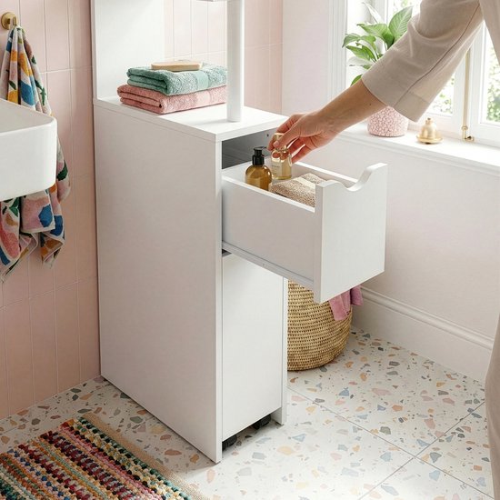Witte opberger met lades en planken in een badkamer, hand pakt flesjes uit lade.