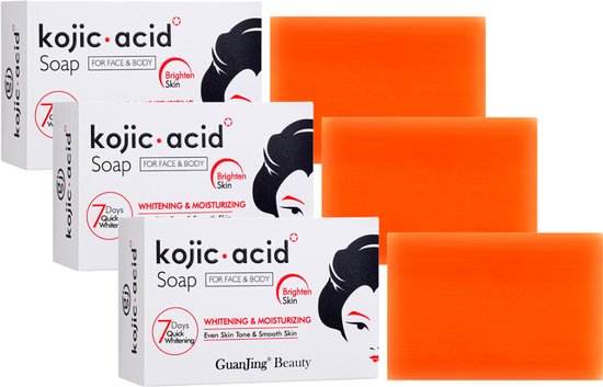 Drie doosjes Kojic Acid zeep met drie oranje zeepjes ernaast.