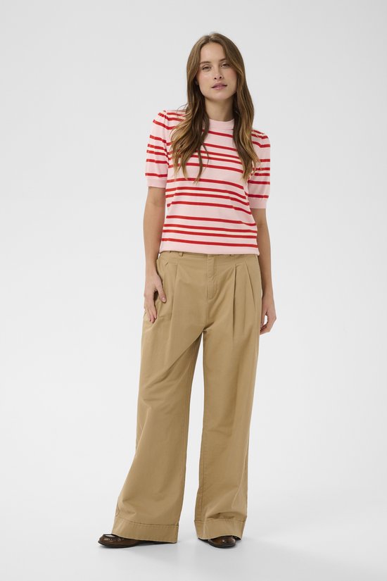 Vrouw, model, draagt roze trui met rode en witte strepen, beige wijde broek.