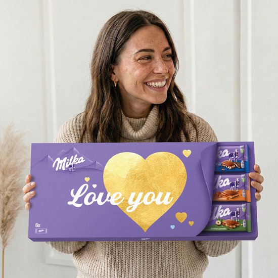 Een vrouw houdt een Milka 'Love you' doos vast. De paarse doos heeft een gouden hart en de tekst 'Love you'.