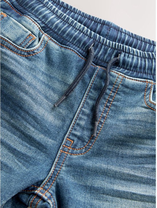 Detail van de tailleband en het trekkoord van een jongens jeans met een blauwe wassing.