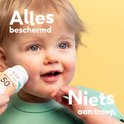 Gezicht van een baby die wordt ingesmeerd met Naïf zonnebrand stick SPF 50, met tekst 'Alles beschermd' en 'Niets aan troep'.
