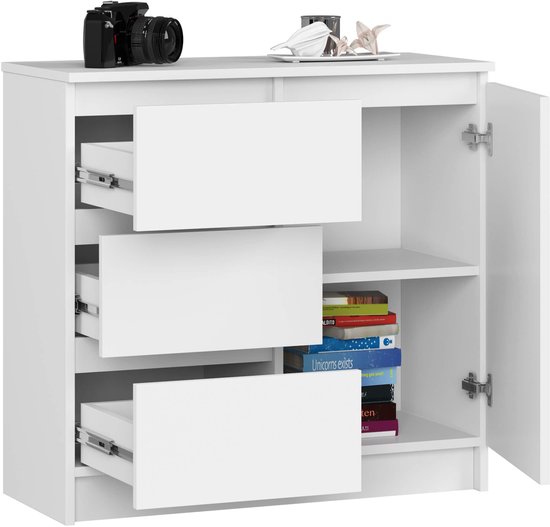 Witte ladekast met 3 open lades en een open deur. Boeken en decoratie op de planken. Camera bovenop.
