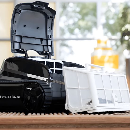 Zwarte Wybot zwembadrobot met open deksel en wit filtermandje, staand op een houten ondergrond.