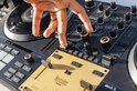 Hand bedient gouden crossfader op een zwarte DJ-controller. Zichtbaar Hercules logo.