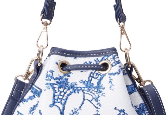 Close-up van sluiting en hengsels van een donkerblauwe emmer tas met wit canvas en blauw Chinoiserie patroon.