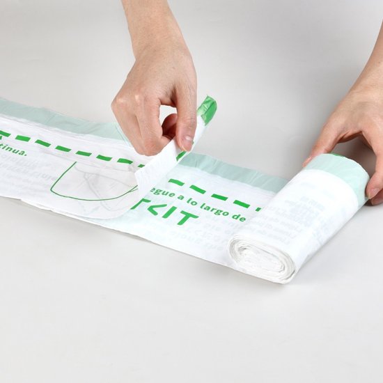 Handen scheuren een PETKIT vuilniszak af van een rol met groene randen.