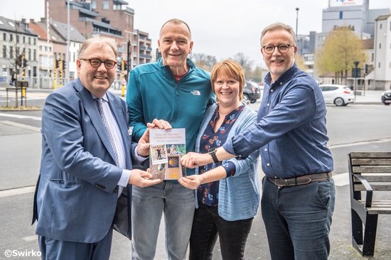 Vier personen, twee mannen en twee vrouwen, tonen een boek met de titel 'Stap voor stap naar Santiago de Compostela'.