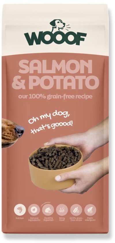 Zalm & Aardappel 100% graanvrij hondenvoer van WOOOF. Een hond ruikt aan een kom met brokjes die door handen wordt vastgehouden.