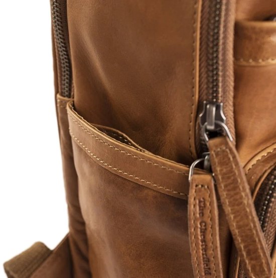 Detailopname van een cognac leren rugzak met rits en leren label.