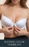 Model sluit een witte push-up bh met een voorsluiting. De bandjes zijn transparant. Tekst: SLUITING AAN DE VOORKANT.