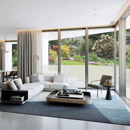 Licht interieur met witte hoekbank, dressoir, grote glazen schuifdeuren naar een tuin.