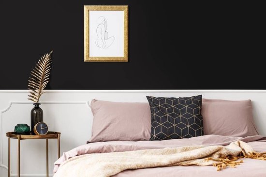 Een slaapkamer met een zwart bed en pastelkleurige kussens, met een gouden lijst aan de muur.