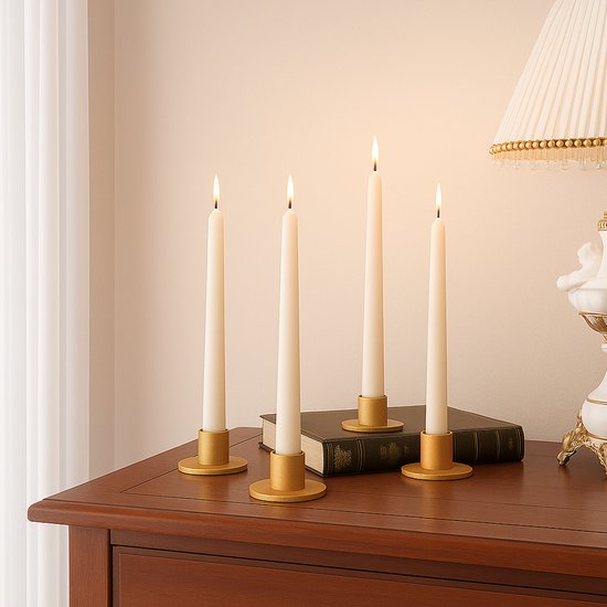 Vier witte kaarsen in gouden kaarthouders staan op een houten tafel voor een boek.