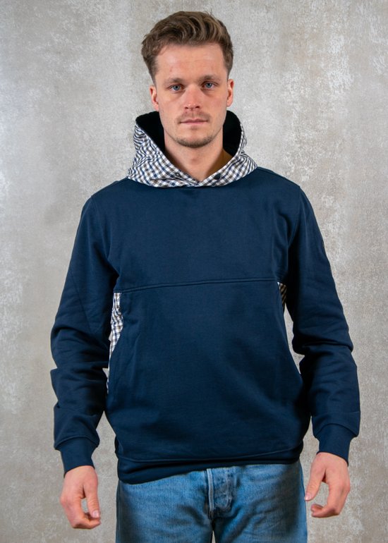 Man draagt donkerblauwe hoodie met geblokte kraag en zijpanelen.