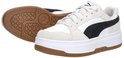 Witte leren Puma sneakers met beige suède, zwarte streep en bruine zool; een sneaker staat rechtop, de ander ligt plat.