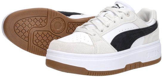 Witte leren Puma sneakers met beige suède, zwarte streep en bruine zool; een sneaker staat rechtop, de ander ligt plat.