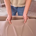 Een vrouw houdt een beige stof vast, de rand van een reisbedje.