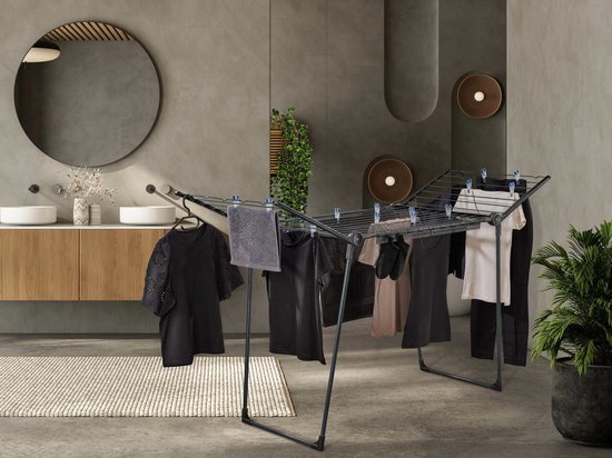 Étendoir noir avec vêtements, serviette et cintres dans une salle de bain.