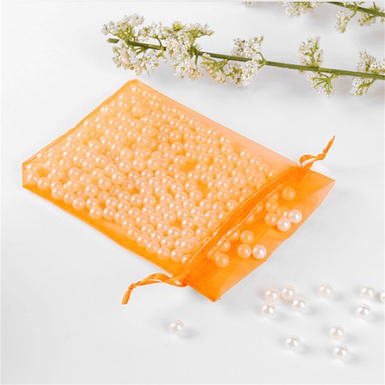 Een oranje organzazakje gevuld met parels, met enkele parels ernaast.
