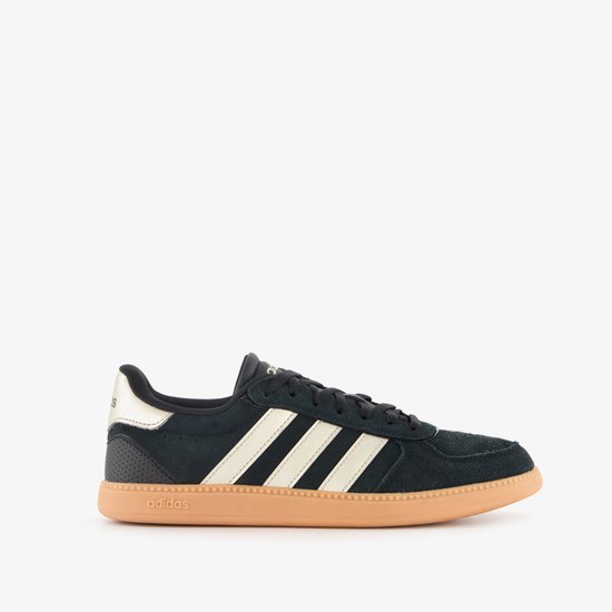 Zwarte Adidas sneaker met gouden strepen en gummi zool, zijaanzicht.