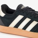 Close-up van de beige Adidas strepen op een zwarte suède sneaker met beige zool.