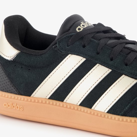 Close-up van de beige Adidas strepen op een zwarte suède sneaker met beige zool.