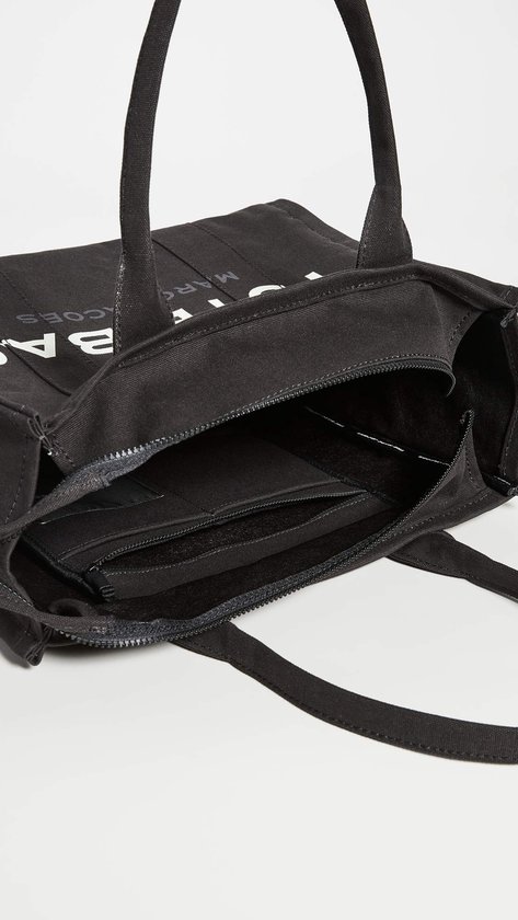 Binnenkant van zwarte canvas tas van Marc Jacobs met ritsvakken.