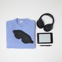Een zwart slaapmasker, een lichtblauwe trui, koptelefoon en een e-reader.