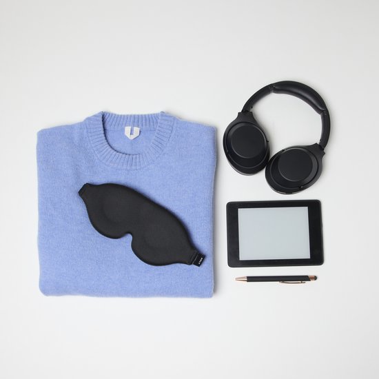 Een zwart slaapmasker, een lichtblauwe trui, koptelefoon en een e-reader.