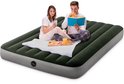 Een man en vrouw zitten op een donkergroen Intex luchtbed. De man leest een boek, de vrouw kijkt op haar telefoon.