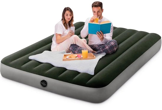 Een man en vrouw zitten op een donkergroen Intex luchtbed. De man leest een boek, de vrouw kijkt op haar telefoon.