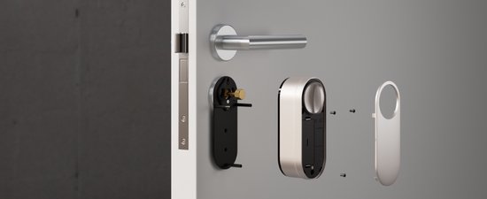 Zilverkleurige deurklink, metalen frame, slotonderdelen en schroeven op grijze deur.