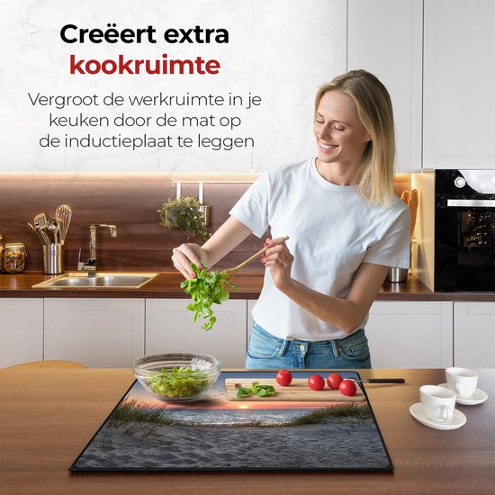 Een vrouw kookt boven een inductiebeschermer met een strandzonsondergang. De beschermer vergroot de werkruimte.