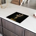 Zwarte inductiebeschermer met boeket bloemen op een gouden voetstuk, op een wit aanrecht.