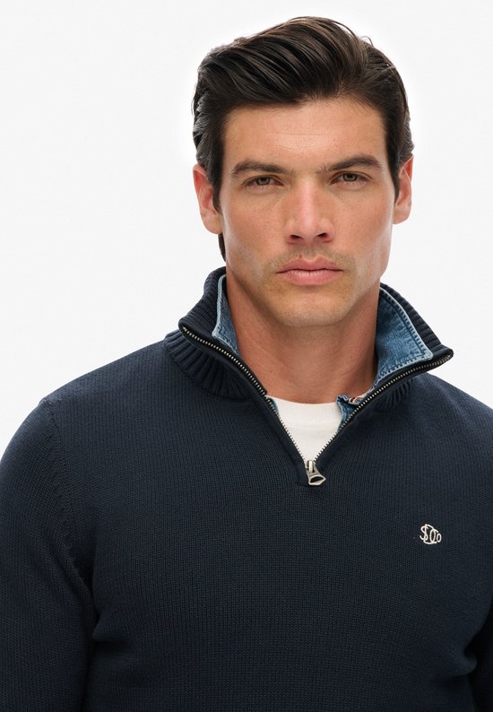 Donkerblauwe trui met halssluiting met rits en denim kraag, close-up.