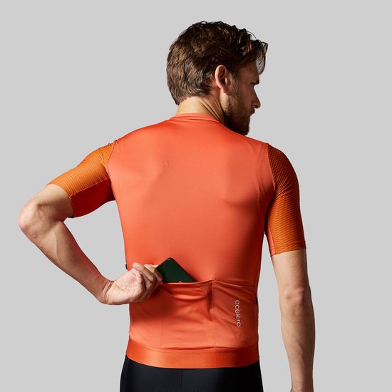 Man met oranje wielershirt, laat achterzakken zien. Op de rug het 'acelera' logo.