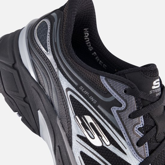 Detail van de zijkant van een zwarte Skechers sneaker met 'Slip-ins' logo en zilverkleurige lijnen.