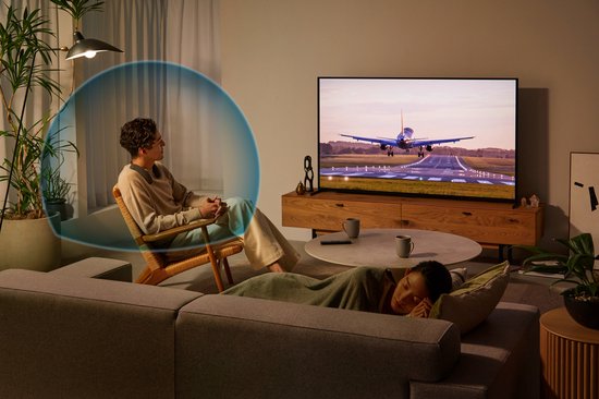 Man luistert naar audio met nekband speaker en blauwe geluidsgolven om hem heen.