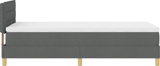 Donkergrijze boxspring met wit matras, donkergrijze hoofdbord en houten poten.