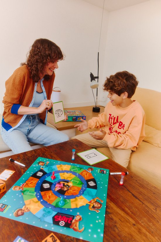 Vrouw met bruine vest en blauwe kraag, met een kaart met een telefoon, lachend naar jongen met oranje trui.