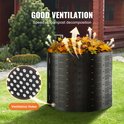 Zwarte compostbak met ventilatiegaten, gevuld met bladeren, buiten op het gras.