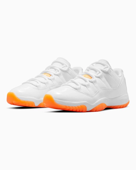 Paar witte lage Nike Air Jordan 11 sneakers met oranje buitenzolen en veters.