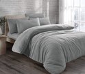 Een grijs teddy fleece dekbed met kussens op een bed in een slaapkamer met winterse sfeer.