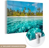 MuchoWow® Glasschilderij 90x60 cm - Schilderij acrylglas - Uitzicht op een strand met palmbomen vanuit het water - Foto op glas - Schilderijen